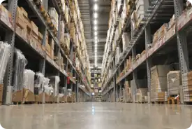 Aisle of warehouse shelves filled with boxes and pallets for storage and distribution.